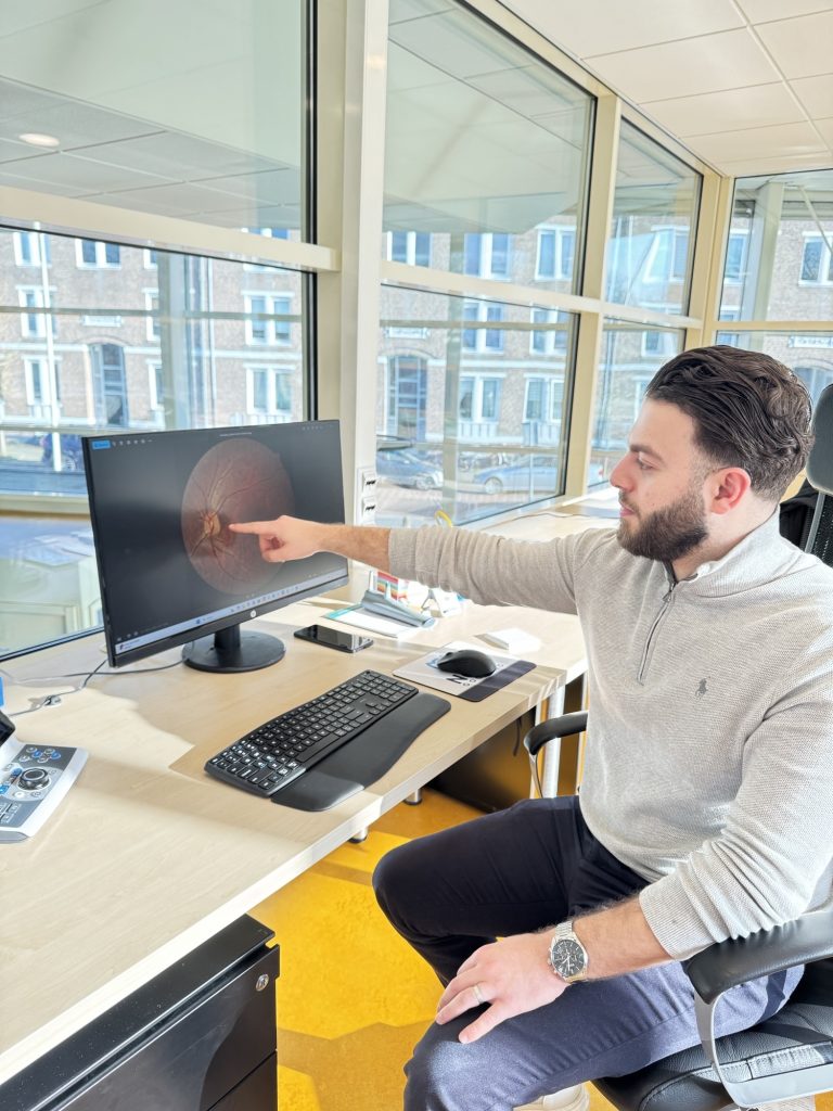 Optometrist bespreekt de beelden van het oogonderzoek aan de hand van het scherm